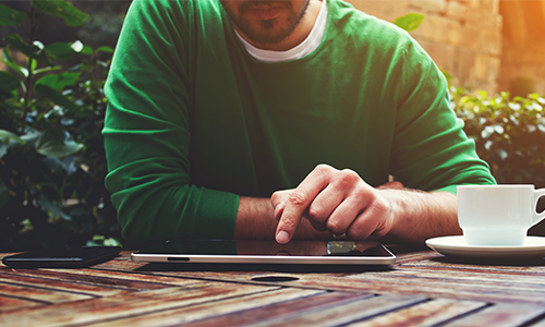 Man browsing content on tablet device outdoors